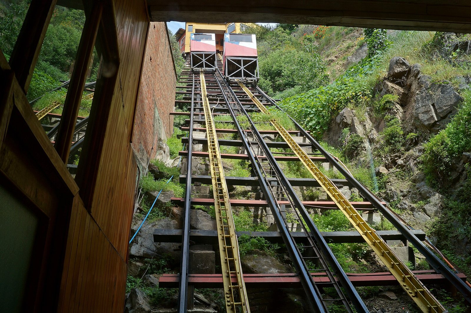 View up the steep twin-rail track of the Ascensor Concepción funicular in Valparaíso, with a wooden car at the upper station